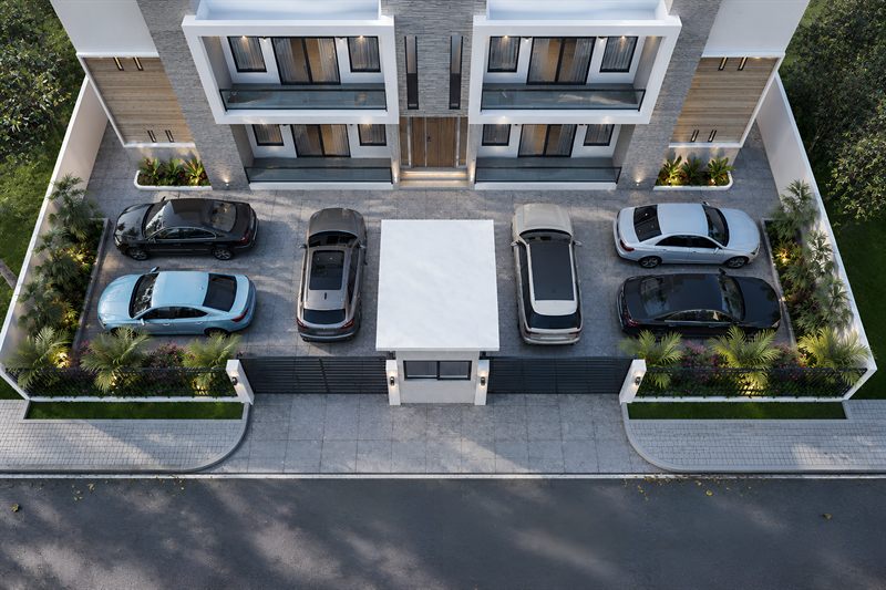 The forecourt from above: eight cars parked either side of the guard house, planted beds along both boundaries, and the building's balconies and timber front doors across the top.