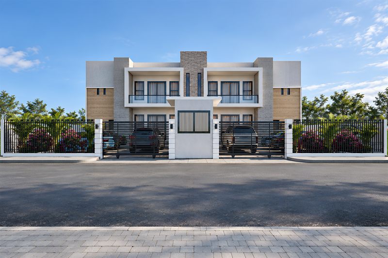 The Adenta Apartment Project from the road: two storeys faced in pale stone and white render, balconies on the upper floor, and cars parked behind the railings between beds of bougainvillea.