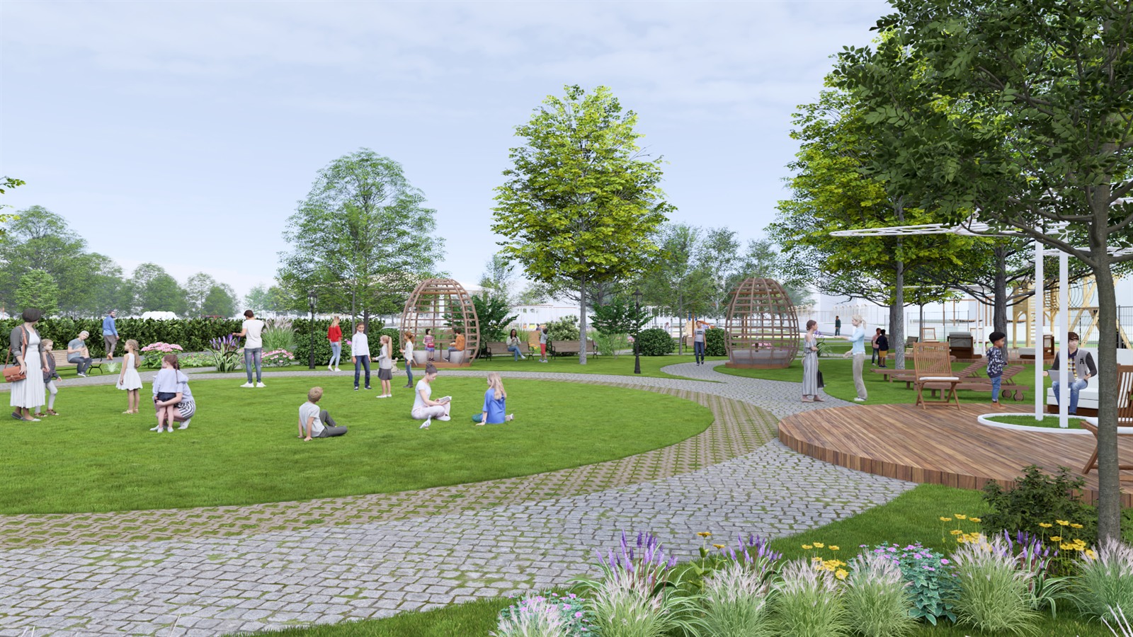 The lawn in use, with the cobbled path curving through it, timber pods behind and a raised timber deck to the right.