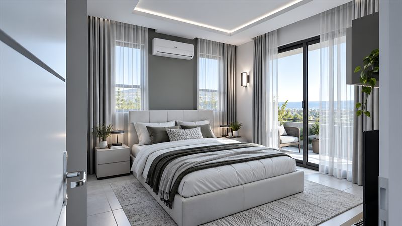 A bedroom: a double bed with a wide upholstered headboard between two bedside tables, curtains across the windows either side of it, a split air conditioner on the wall above, and a sliding door at the right onto a balcony with a chair.